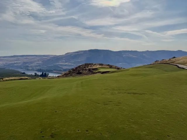Golfers on a tee at Scarecrow, with the mountains behind them.