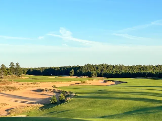 A golfer hitting a shot at Sedge Valley, with the sandy fairway ahead.