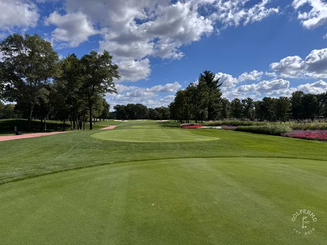 A fairway at SentryWorld, with trees along the hole and water in view.