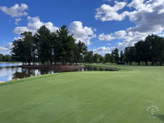 A wide view at SentryWorld, the fairway running toward a tree line.