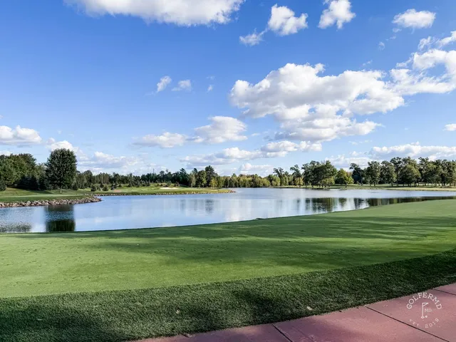 A tee at SentryWorld looking down a fairway lined with trees.