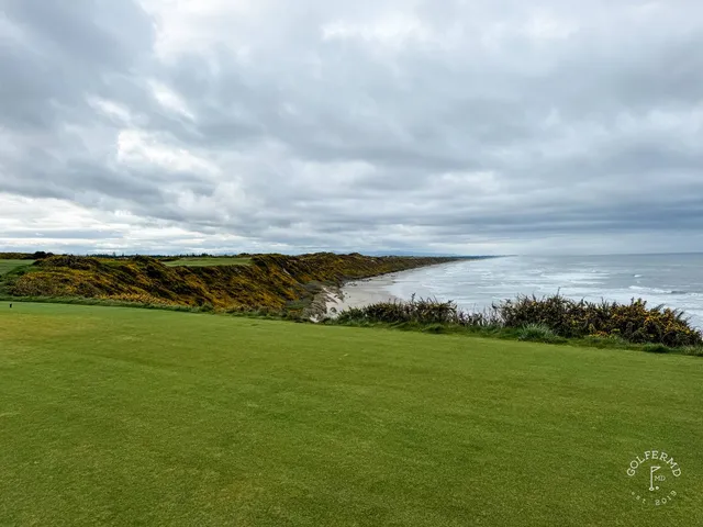 A golfer hitting a shot at Sheep Ranch, with the ocean ahead.