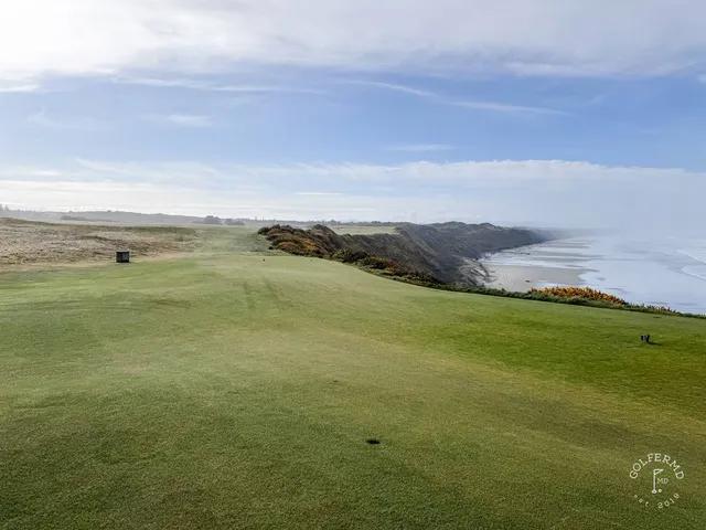 Golfers walking a fairway at Sheep Ranch, with the ocean beside the hole.