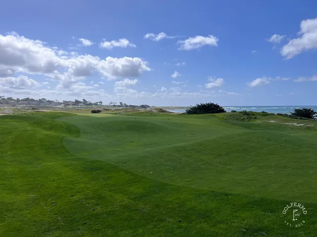 A green and flagstick in the dunes at The Links at Spanish Bay, with the ocean on the horizon.