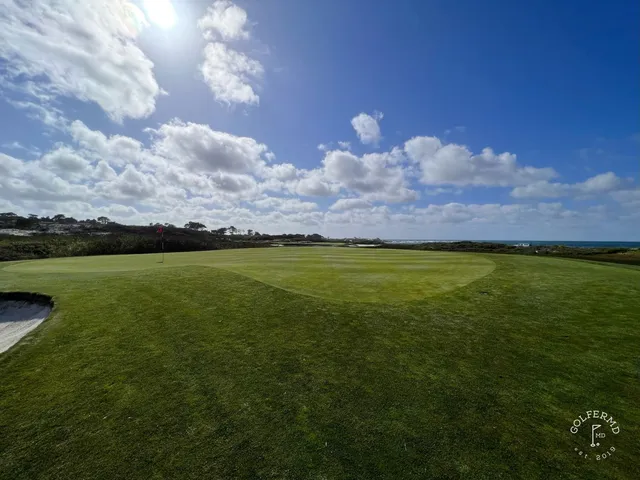 A green and flagstick in the dunes at The Links at Spanish Bay, with the ocean beyond.
