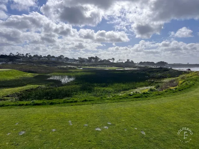 A fairway through the dunes at The Links at Spanish Bay, with cypress trees and the ocean ahead.