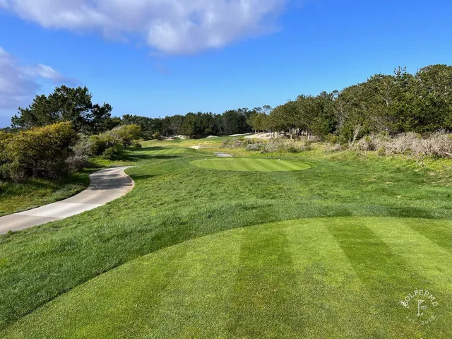 A green and flagstick beside the ocean at The Links at Spanish Bay.