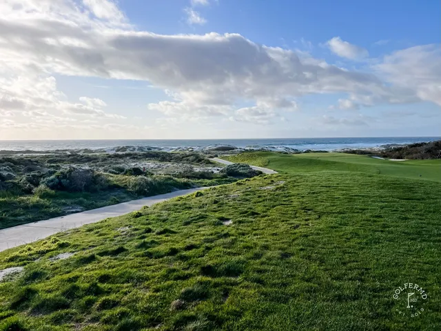 A green and flagstick above the ocean at The Links at Spanish Bay, with a bunker in front.