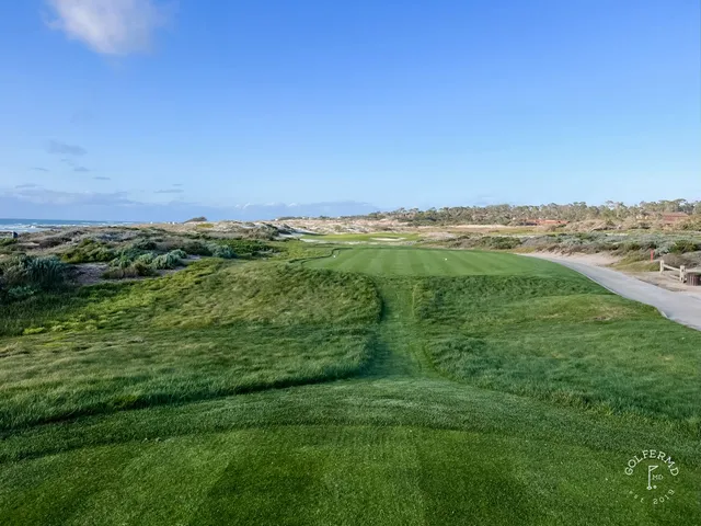 A narrow path through the dunes at The Links at Spanish Bay, with the ocean ahead.