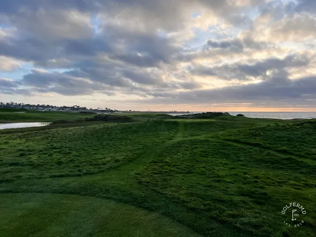 A green and flagstick on the edge of the dunes at The Links at Spanish Bay, with the ocean below.