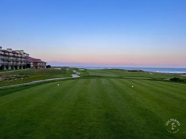 A green and flagstick in the dunes at The Links at Spanish Bay, with the ocean on the horizon.