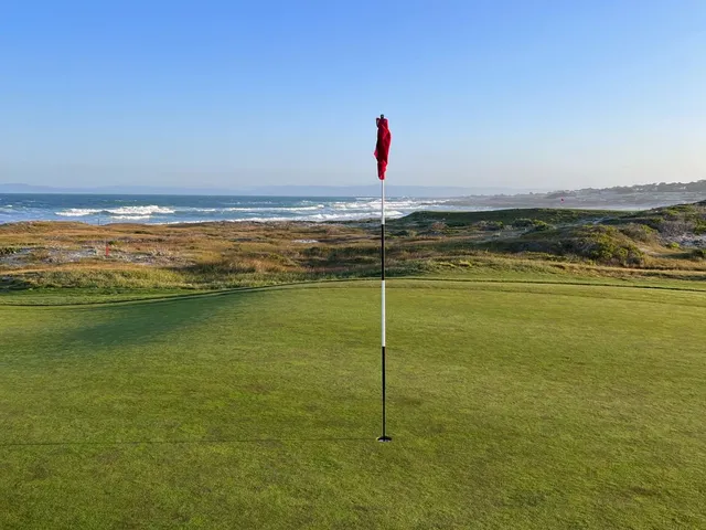 A fairway through the dunes at The Links at Spanish Bay, with cypress trees along the hole.