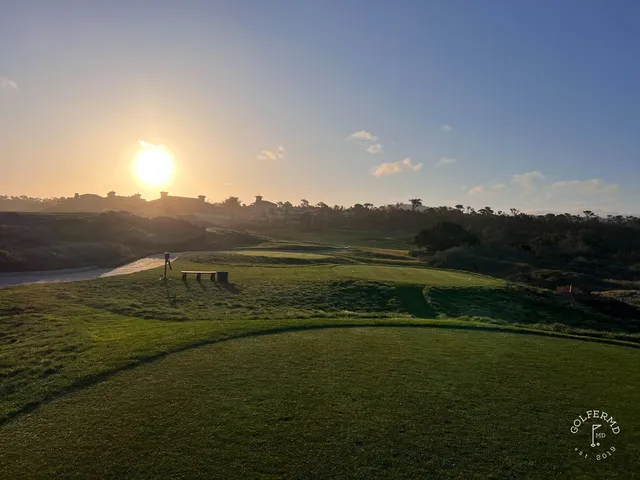 A green and flagstick above the ocean at The Links at Spanish Bay, with a bunker short of the green.