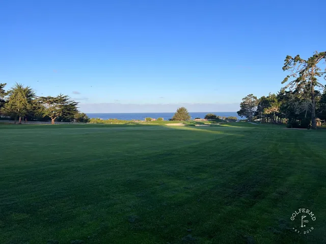 A green and flagstick above the ocean at Spyglass Hill Golf Course, with the coastline beyond.