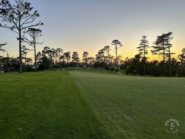A green and flagstick on the edge of the dunes at Spyglass Hill Golf Course, with the ocean below.
