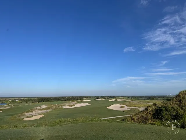A green and flagstick at the Blue Course, with a sand bunker in front and the Streamsong lodge behind the hole.