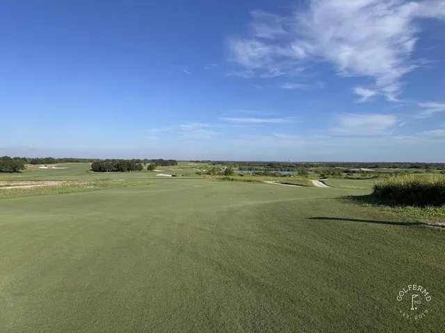 A fairway at the Blue Course winding through dunes and long grass, with a green in the distance.