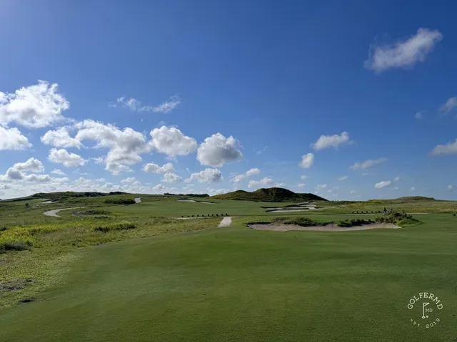 A green and flagstick at the Blue Course, with a sand bunker beside the green and the Streamsong lodge behind it.