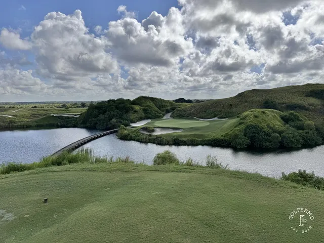A fairway at the Blue Course running through dunes toward a green, with the Streamsong lodge on the horizon.