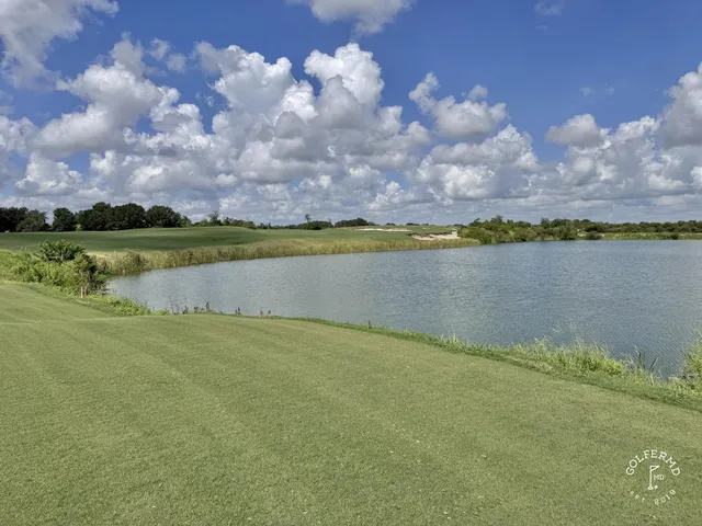 A golfer putting on a green at the Blue Course, with sand bunkers and the Streamsong lodge behind the hole.