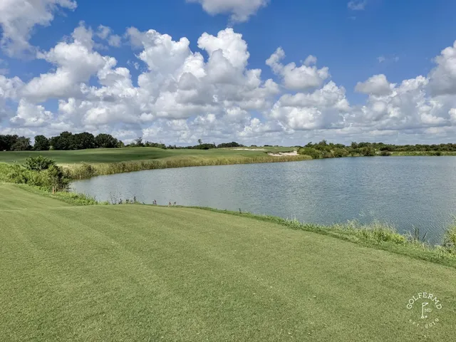 A golfer putting on a green at the Blue Course, with a sand bunker and the Streamsong lodge in the background.