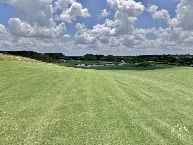 A green and flagstick at the Blue Course, with a sand bunker in front and the Streamsong lodge behind the hole.