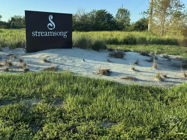 A green and flagstick at Streamsong's Red Course, with a sand bunker in front and the Streamsong lodge behind the hole.