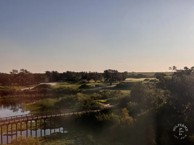 A wide sandy hole at the Red Course, with long grass, a distant green, and the Streamsong lodge on the horizon.