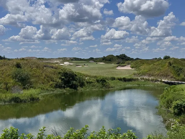 A fairway at the Red Course curving through sandy ground toward a green and the Streamsong lodge.