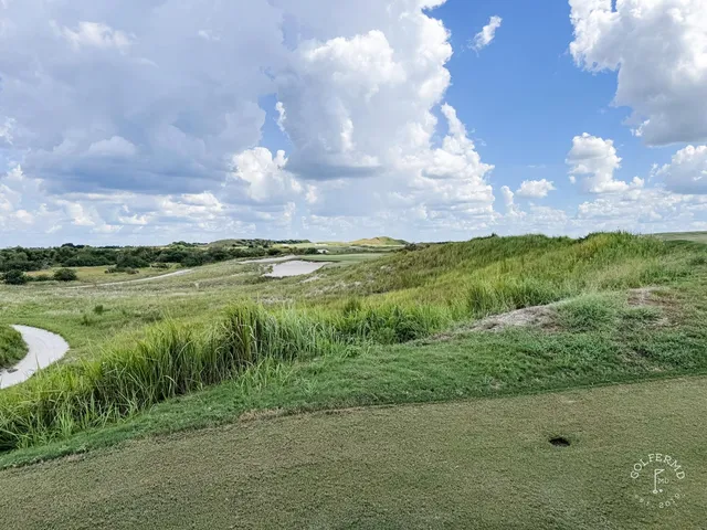 A green and flagstick at the Red Course, with a deep bunker beside the green and the Streamsong lodge behind it.