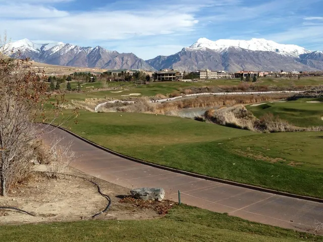 A green and flagstick at Thanksgiving Point, with a bunker in front and the mountains behind the hole.