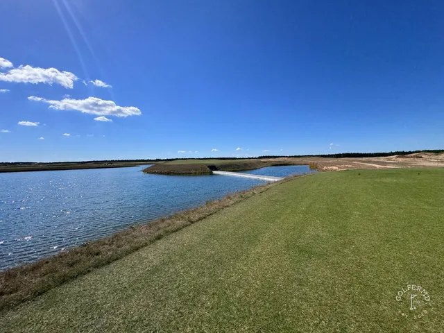 A green and flagstick at The Lido, a bunker in front and the sand hills beyond.