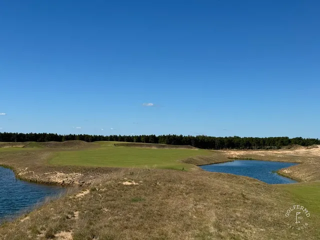 A golfer hitting a shot at The Lido, with the sandy hole ahead.