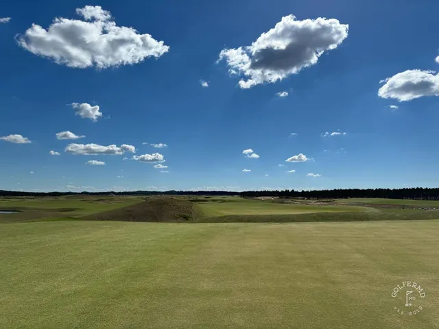 A tee at The Lido looking across sand toward a green.