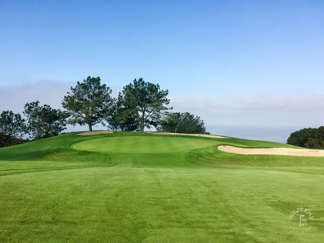 A green and flagstick on the cliffs above the ocean at Torrey Pines North Course, with a bunker in the foreground.