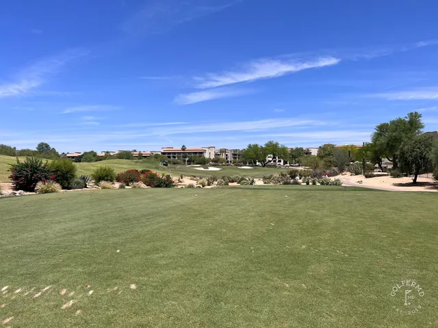 A group posing for a photo at TPC Scottsdale, with the McDowell Mountains behind them.