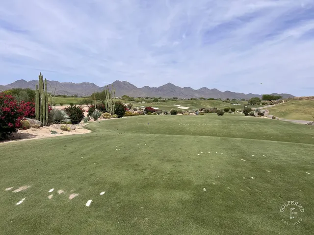 A green and flagstick at TPC Scottsdale, seen from a rise, with the McDowell Mountains behind the hole.