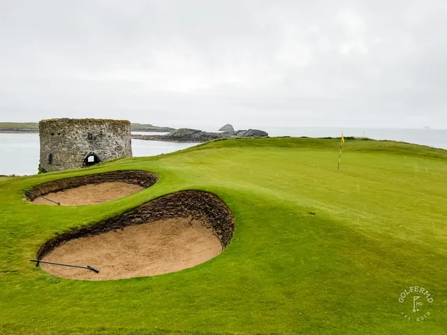 Golfers walking a fairway at Tralee, with the ocean on the left.