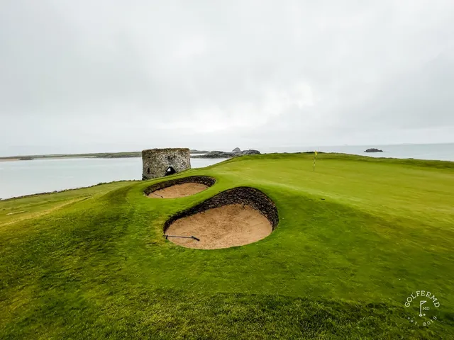 A green and flagstick at Tralee, a deep bunker short of the hole and the dunes behind.