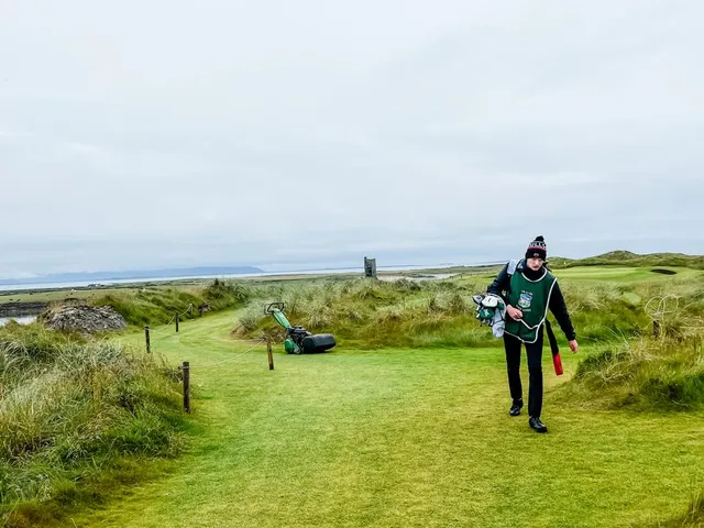 A green at Tralee with the flagstick, sand around the hole, and the sea beyond.