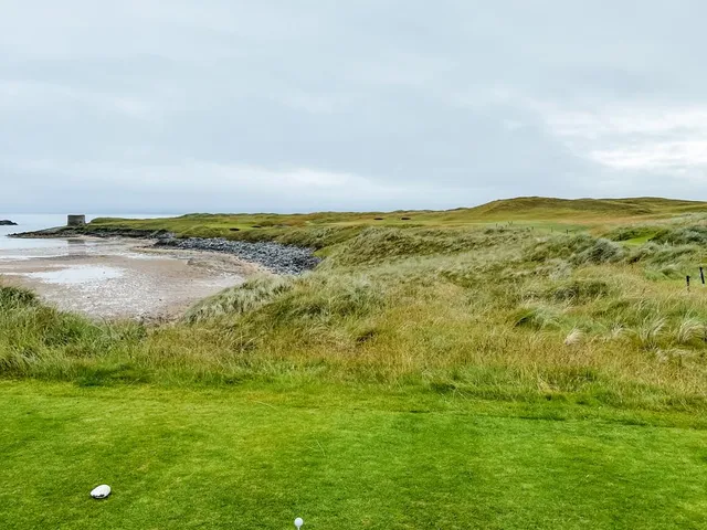 A close flagstick at Tralee, with the water just beyond the green.