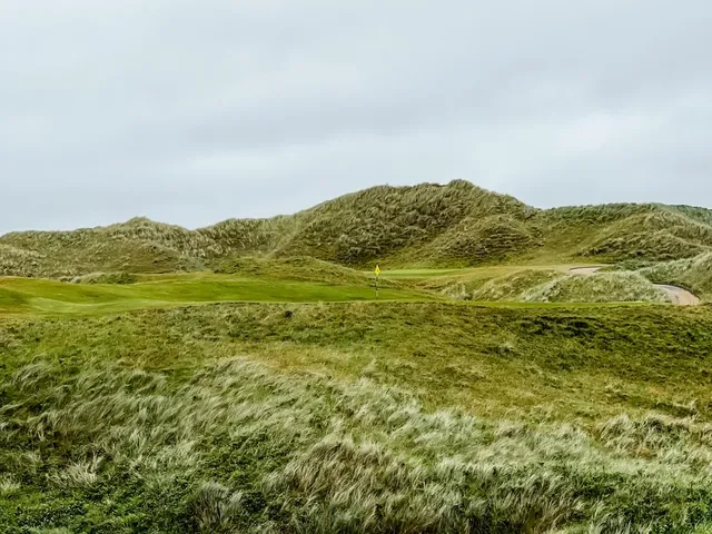 A green at Tralee seen from behind the hole, the fairway running back through the dunes.