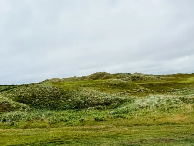 The ocean along the left of a fairway at Tralee, with marram grass on the right.