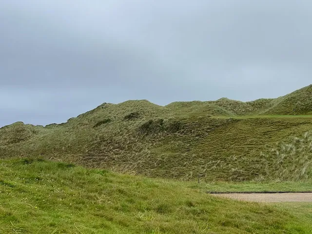 A fairway at Tralee crossing a saddle in the dunes, the ocean showing beyond.