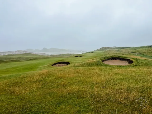 A wide links hole at Tralee, with dunes, grass, and the sea and no trees in sight.