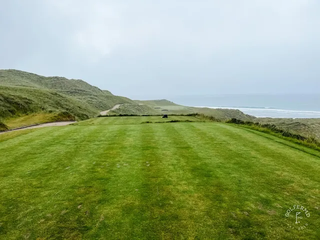 A golfer walking off a green at Tralee, the next tee set in the marram.