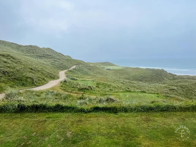 A fairway at Tralee pale against the darker dunes, with the bay beyond.