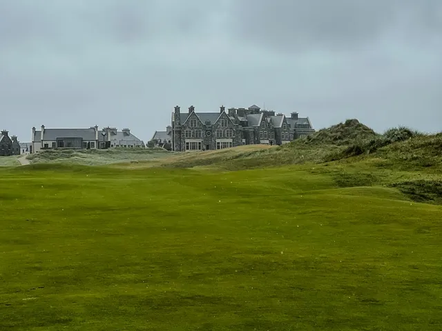 A golfer hitting a shot at Doonbeg, with the water ahead.