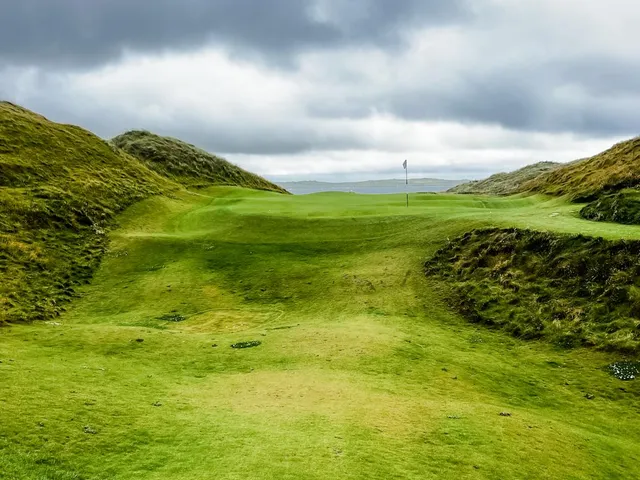 A close view of a flagstick at Doonbeg, with a bunker beside the green.