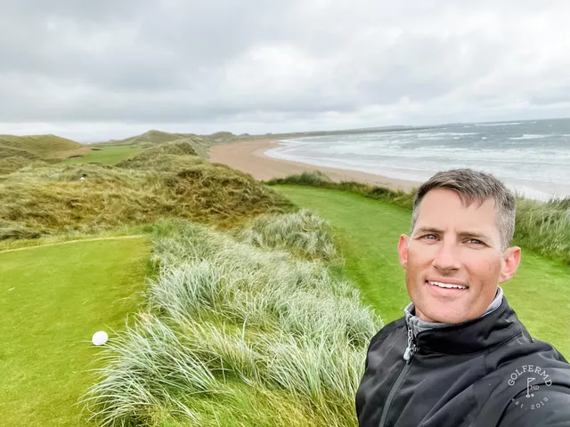 A fairway at Doonbeg bending toward the ocean, with sand along the hole.